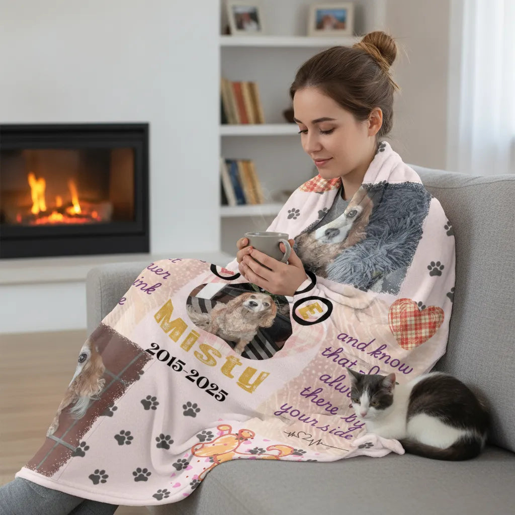 Woman on a sofa wrapped in the memorial photo blanket holding a mug, with a cat asleep beside her