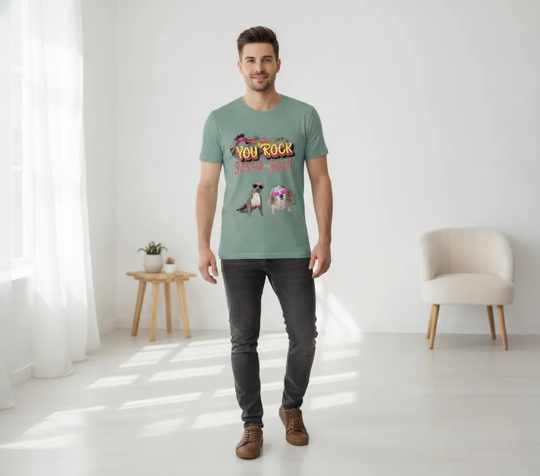 Man standing in a bright room wearing the sage green You Rock t-shirt printed with two dogs in heart-shaped sunglasses