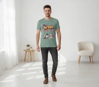 Man standing in a bright room wearing the sage green You Rock t-shirt printed with two dogs in heart-shaped sunglasses
