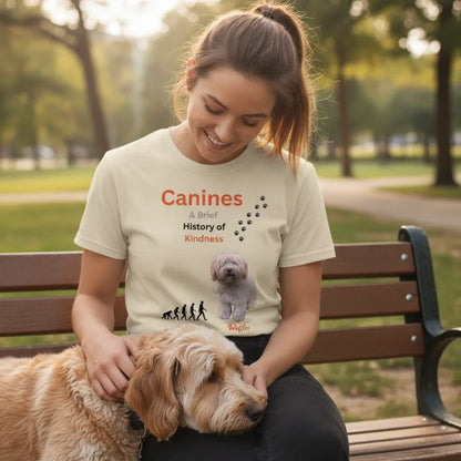 Woman on a park bench with a golden doodle resting against her, wearing the cream Canines history t-shirt