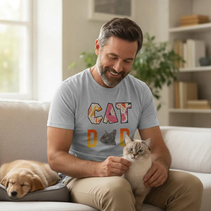 Man on a sofa wearing the grey CAT DAD t-shirt, holding a cream cat with a puppy asleep beside him