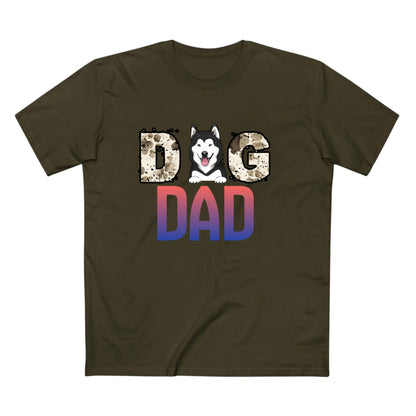 An olive green crewneck t-shirt featuring a graphic print that reads 'DOG DAD'. The letter 'O' is replaced with a cartoon husky dog head, and the letters 'D' and 'AD' below are filled with a red-to-blue gradient pattern, while 'G' has a leopard print texture.