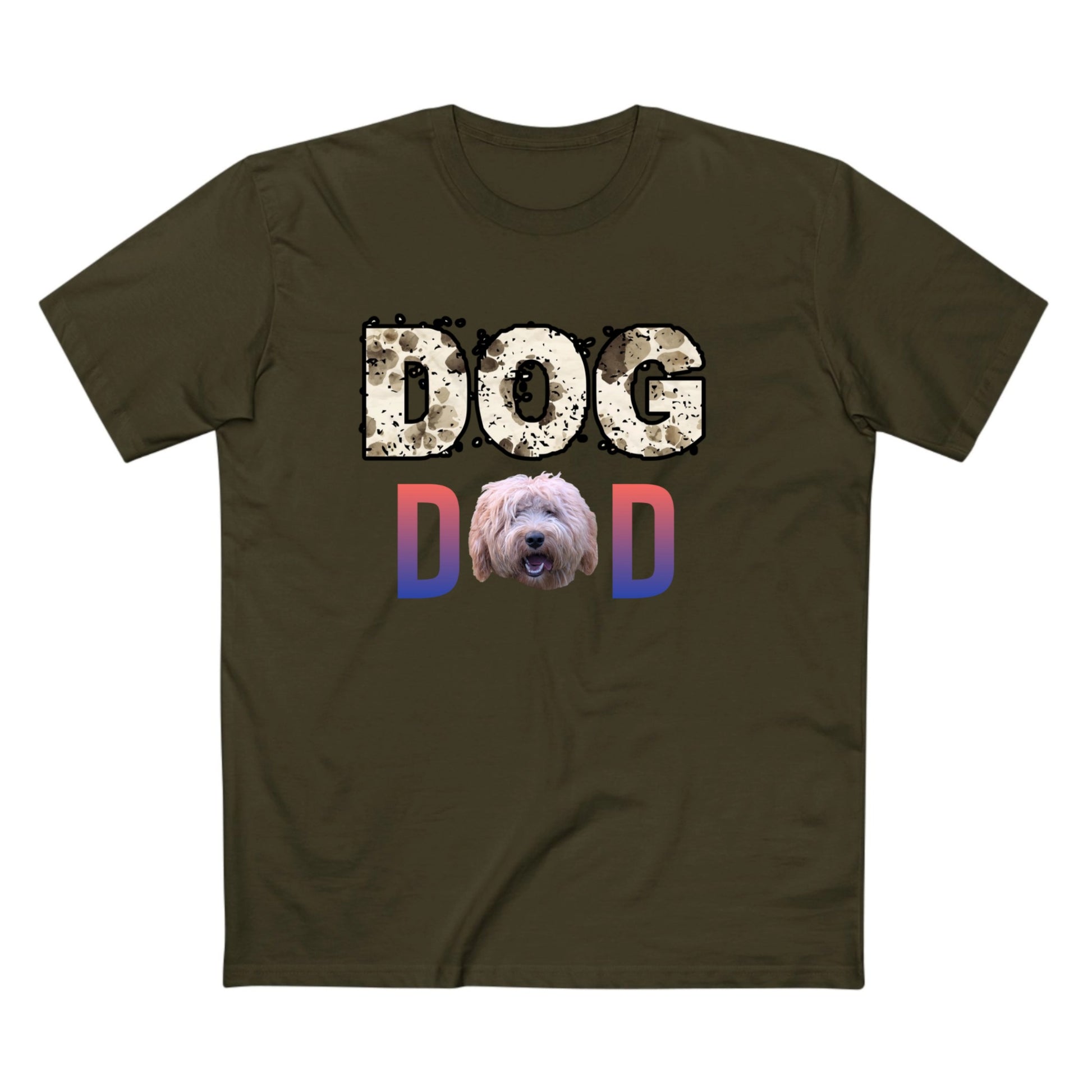 An olive green short-sleeve t-shirt with a graphic on the chest that reads 'DOG DAD'. The 'DOG' text is in a distressed beige pattern, the 'D' is in a blue-to-pink gradient, and the 'D' is also in a blue-to-pink gradient with a shaggy dog face printed inside it.